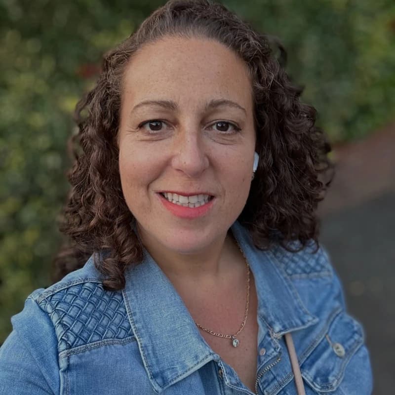 “Hannah Cohen, smiling outdoors in a denim jacket”