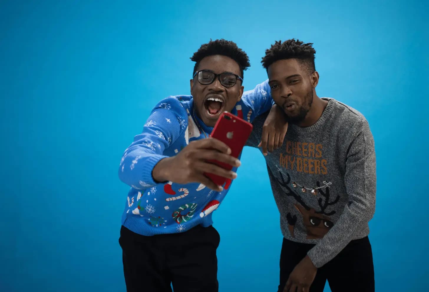 “two men taking a selfie against a blue background”